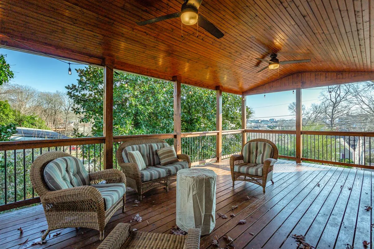 The image captures a tranquil exterior seating area with wicker chairs under a wooden ceiling, overlooking the landscape. This inviting nook is perfect for sunrise coffee, reading, or socializing in a peaceful outdoor setting.