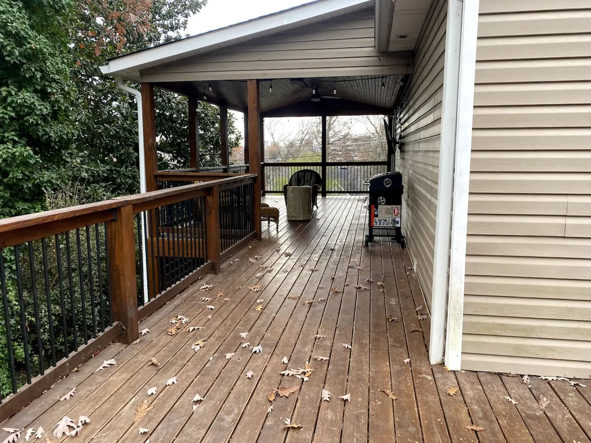 A spacious wooden deck with outdoor seating and a view of the fenced backyard, ideal for gathering with friends or relaxing after exploring the city. The setup invites conversation and leisure, with enough room for a group to enjoy meals or drinks together in the open air.