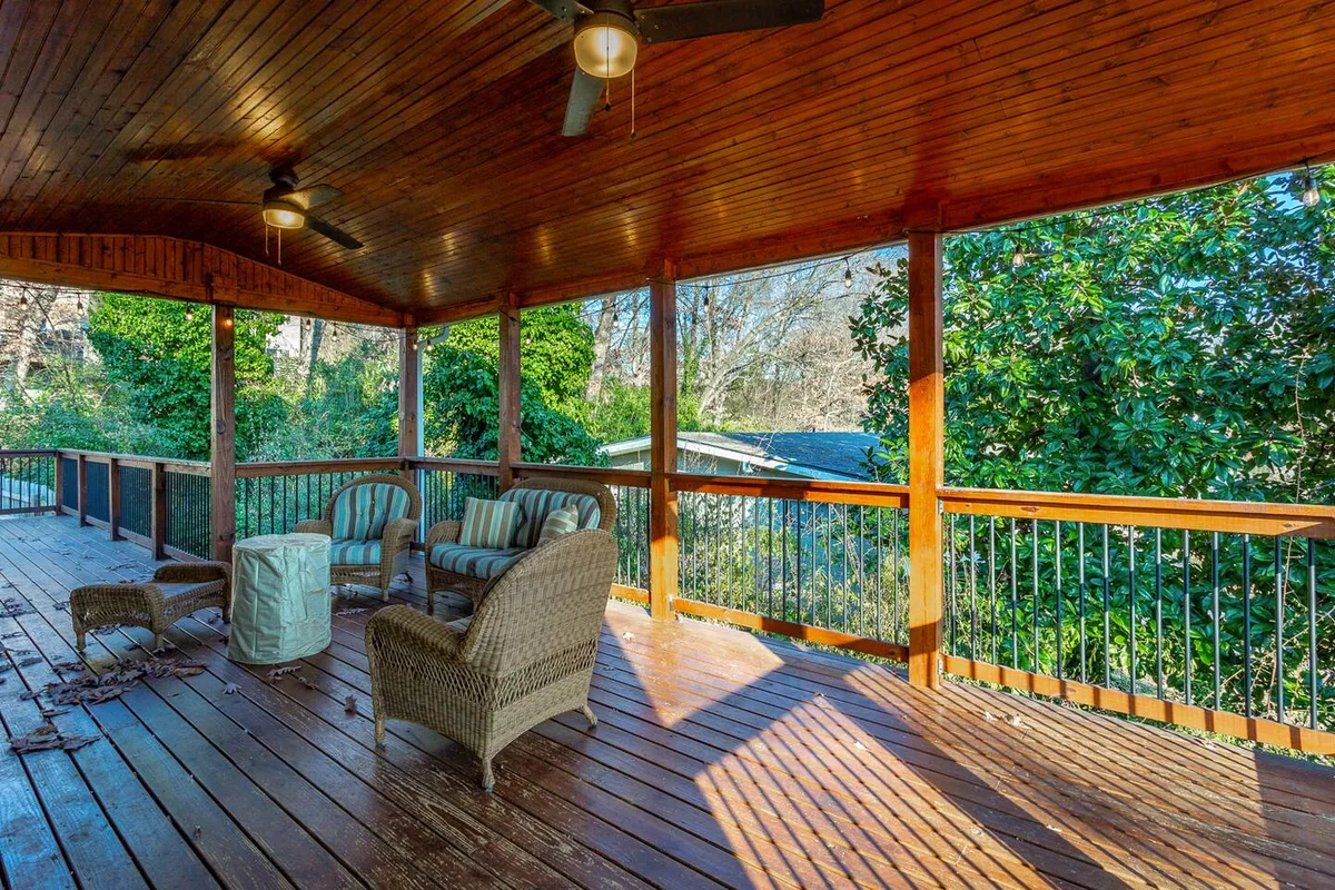 A comfortable outdoor seating area is set on a wooden deck surrounded by natural greenery. The space exudes tranquility, making it perfect for informal meetings, casual conversations, or unwinding after a productive day.
