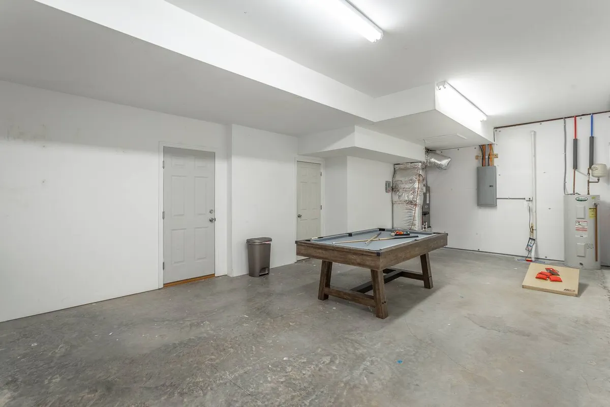 A modern interior recreation space featuring a pool table, adjacent doorways, and an area designed for casual hangouts and friendly competition. The setting is ideal for group entertainment and informal bonding.